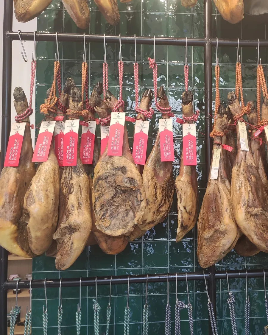 Jamones y paletas de bellota ibérica colgados en la tienda